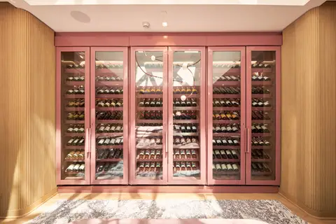 glass-fronted wine cabinets in pink framing along a wood-lined wall