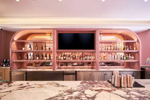 arched backbar with bottle shelving and a screen above the counter