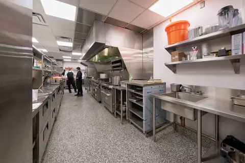 wide view of the cook line with chefs under the exhaust canopy
