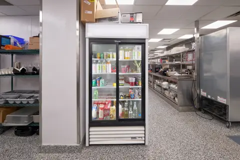 glass-door refrigerator and wire shelving in the back kitchen