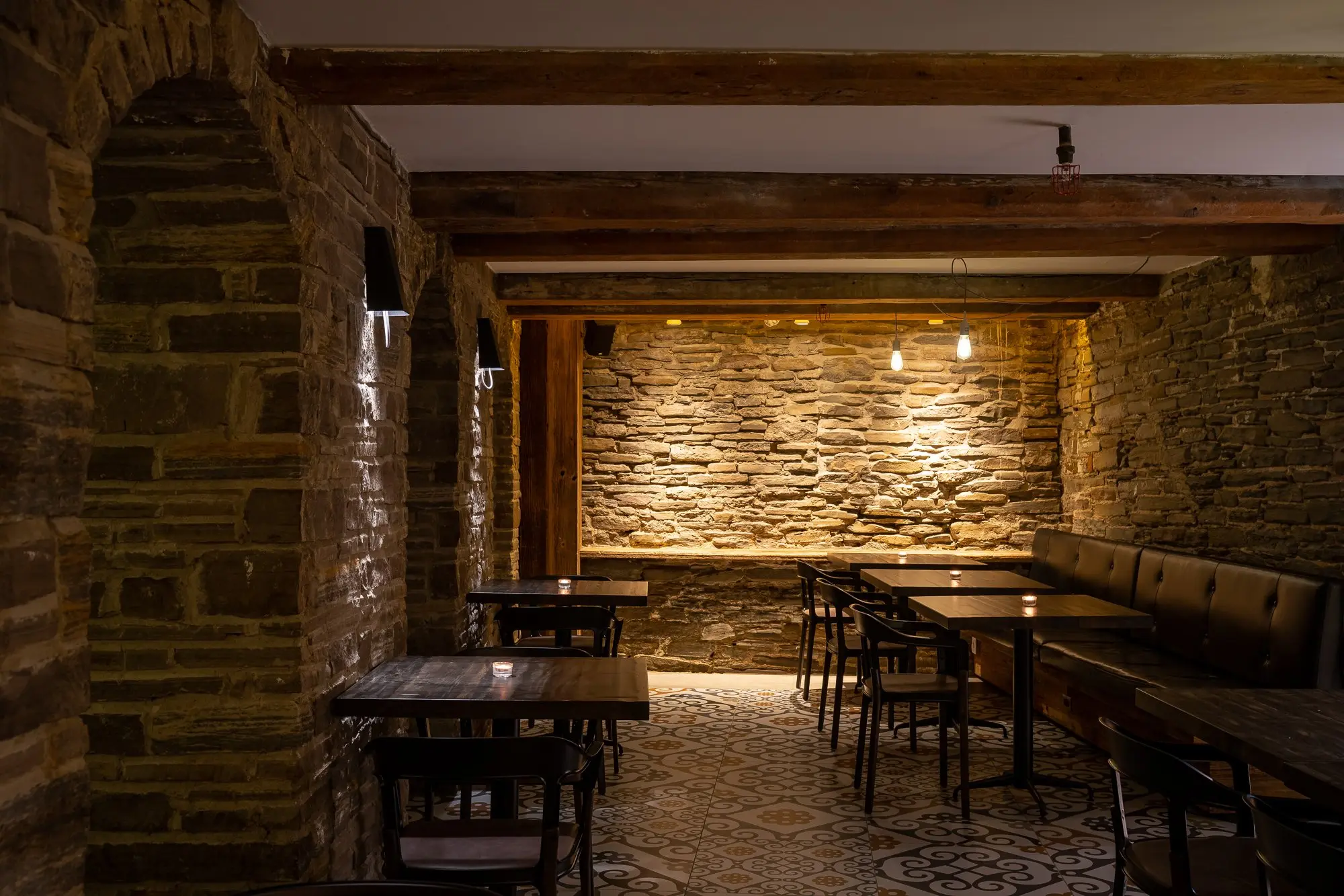 stone-walled dining room with leather banquette and exposed timber beams