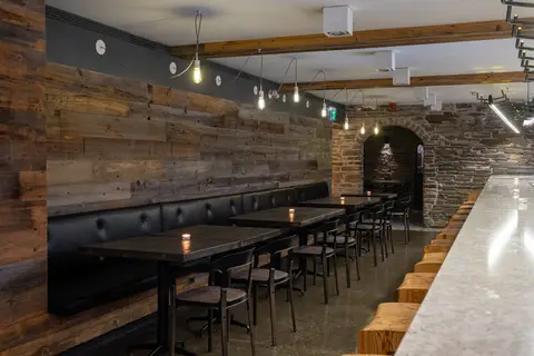 row of two-top tables along a reclaimed timber wall