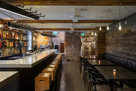 long bar with backlit bottle display and solid timber stools