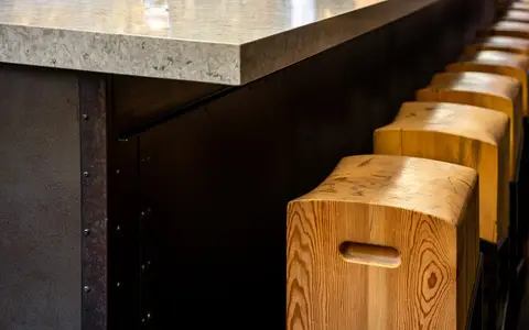quartz bar counter edge above blackened steel and timber block stools