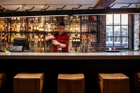 bartender working behind the bar with the bottle wall behind
