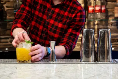 bartender's hands finishing a cocktail on the bar top