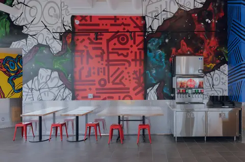 dining tables beside the beverage station and mural wall