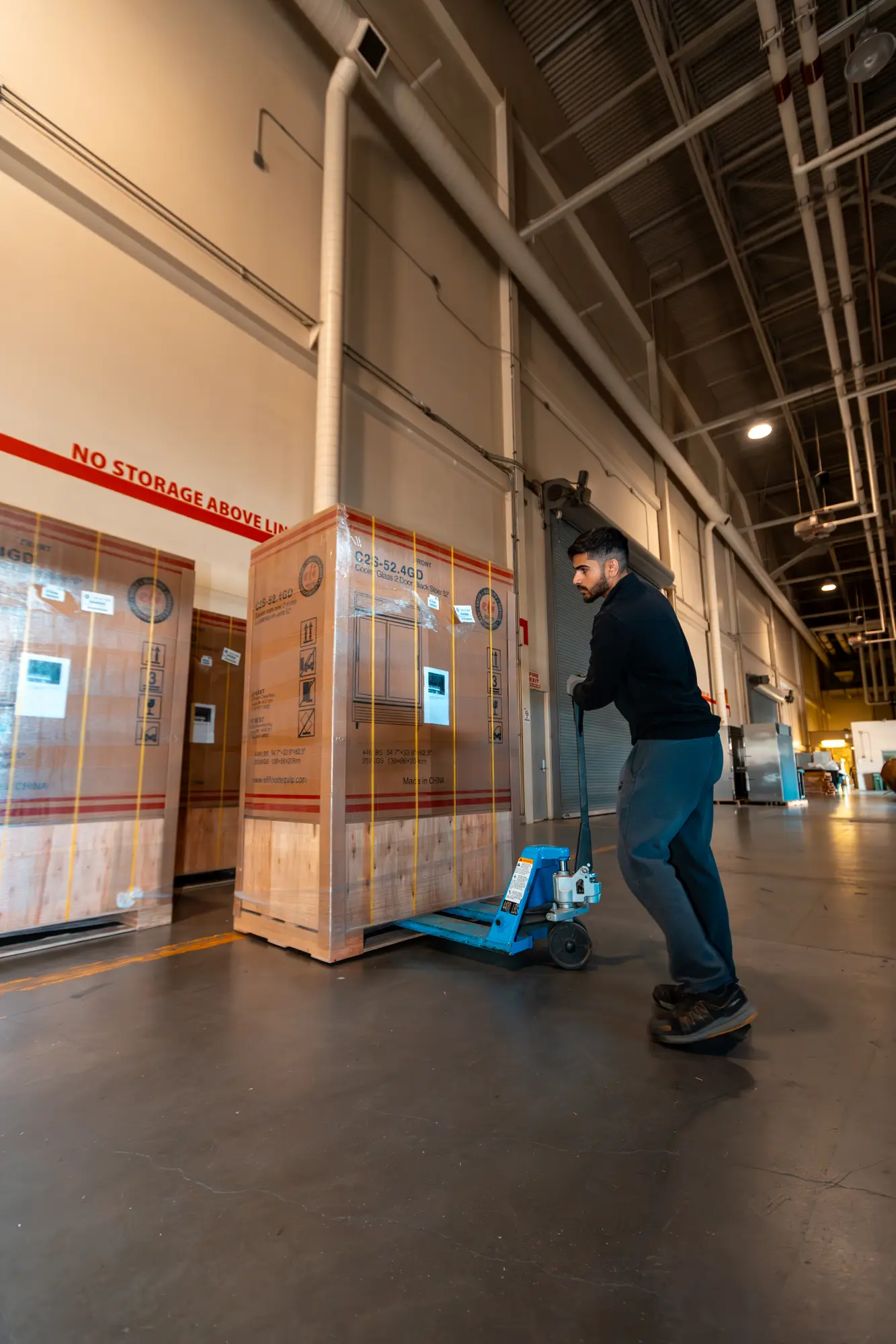 Crated refrigeration equipment moved on pallet jacks inside the venue