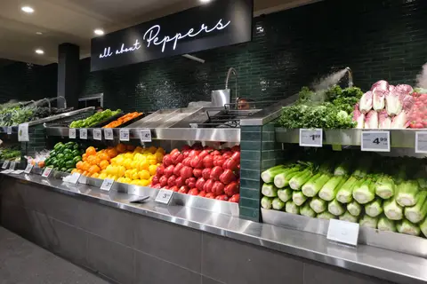 refrigerated pepper and greens display under an All About Peppers sign