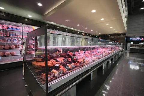 long refrigerated deli case stocked with cured meats