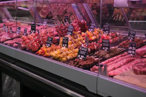 refrigerated butcher case stocked with marinated skewers