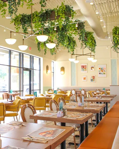 Pür & Simple San Antonio dining room with yellow chairs, banquettes, and greenery