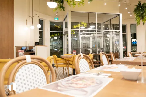Pür & Simple Sherwood Park: Tables, woven chairs, and greenery in the dining room.