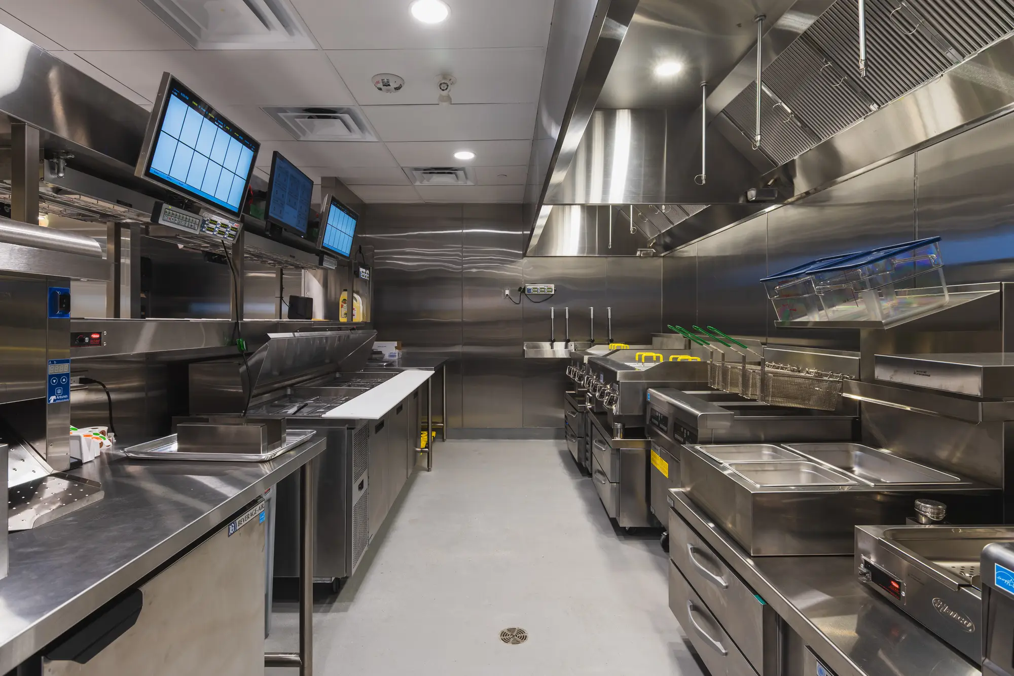 Commercial cook line with griddles and order screens at Shake Shack Square One